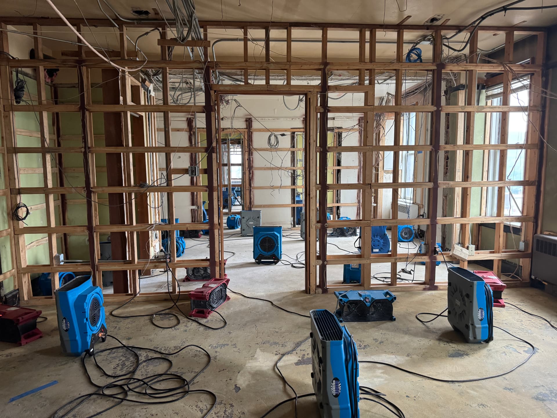 Commercial office floor stripped to studs with air movers running during structural drying
