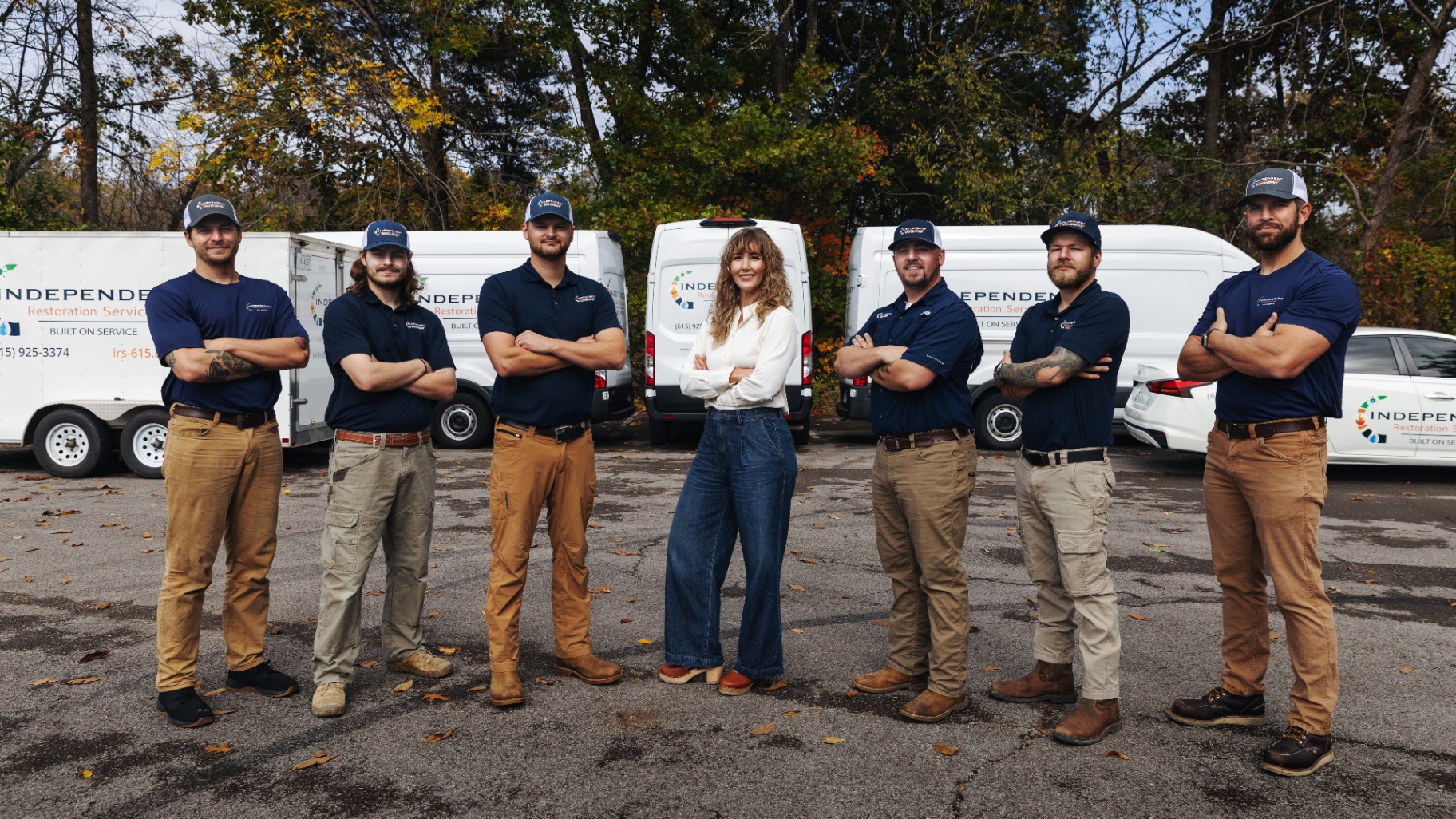 The Independent Restoration Services team standing in front of company vehicles